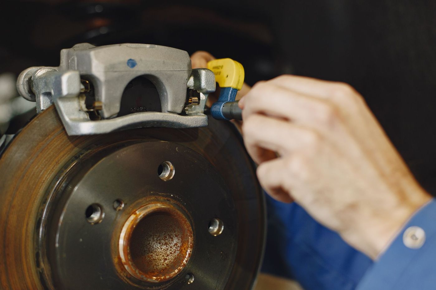 A gloved hand working on a disc brake and caliper with the wheel removed — stock photograph